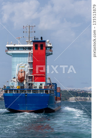 A cargo ship moves through the Bosphorus Strait, reflecting maritime activity and trade during a sunny afternoon, with a scenic backdrop of Istanbul. 135513879