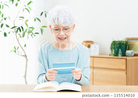 老婦人一邊看著存摺一邊思考 老婦人一邊看著存摺一邊思考 135514010