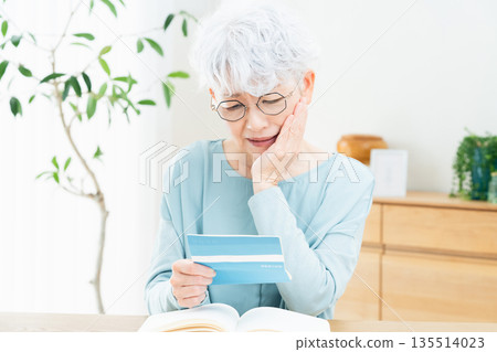 Senior woman thinking while looking at her bankbook 135514023