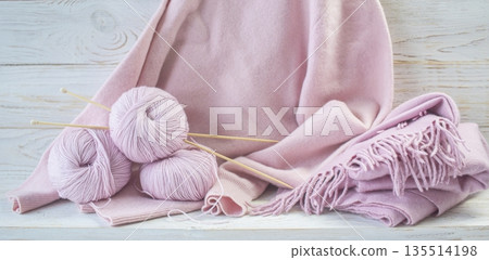 Soft wool pink yarn and knitting needles with a cozy pink cashmere scarf with fringe. 135514198
