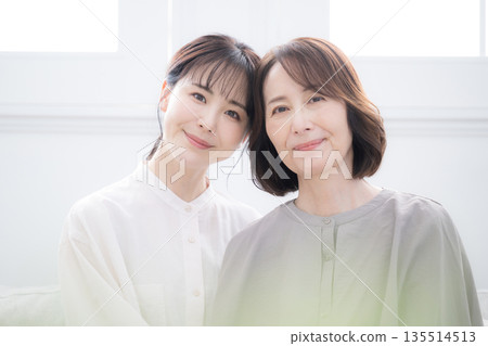 Smiling mother and daughter hugging each other - close up of happy, laughing 135514513