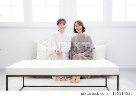 Smiling mother and daughter standing close together, image of happiness, full-body view, looking at the camera Smiling mother and daughter standing close together, image of happiness, full-body view, looking at the camera 135514523