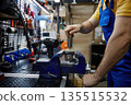A skilled man is working on broken electrical equipment that is securely clamped in a vise 135515532