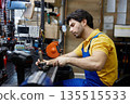 Technician service man repairing a broken power drill inside a busy workshop 135515533