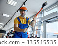 A man worker in overalls and a helmet is holding a hammerhead in a store 135515535