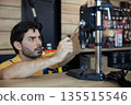 A male worker is diligently working on a drilling machine 135515546