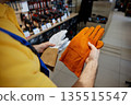 Young worker holds two pairs of gloves 135515547