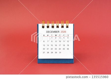 December 2026 white desk calendar on red background. 135515960