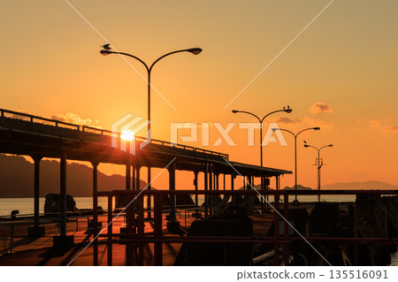 愛媛郡八幡濱港的日落,碼頭和路燈的輪廓在夕陽下若隱若現。 愛媛郡八幡濱港的日落,碼頭和路燈的輪廓在夕陽下若隱若現。 135516091