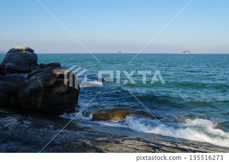 Waves of the turquoise sea.White splashes of waves from the turquoise sea hit the stone shore. 135516273
