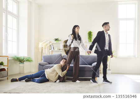 Painful breakup scene with man holding onto woman as she walks away with another Painful breakup scene with man holding onto woman as she walks away with another 135516346