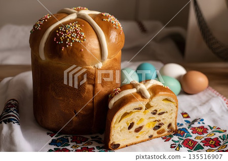 Traditional festive easter kulich (slavic sweet bread) decorated with raisins, white icing, sprinkles, and colored eggs 135516907