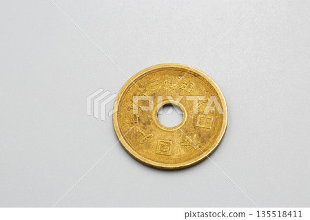 Japanese five yen coin on white surface closeup. Japanese five yen coin on white surface closeup. 135518411