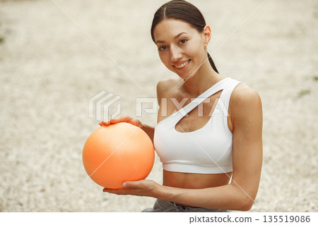 Pretty lady training on a summer beach. Brunette doing yoga. Girl in a sportsuit. 135519086