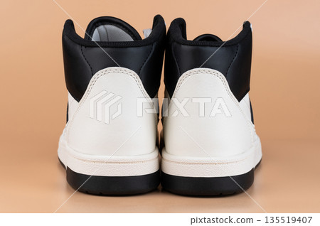 High-top sneakers displayed on neutral backdrop showcasing modern footwear design High-top sneakers displayed on neutral backdrop showcasing modern footwear design 135519407