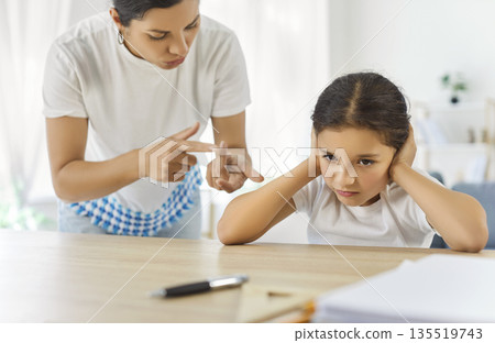 Strict mother pointing fingers as daughter resists, homework conflict at home Strict mother pointing fingers as daughter resists, homework conflict at home 135519743