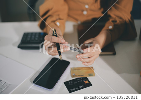 Online payment, Hands of woman holding a credit card and using smart phone for online shopping 135520811