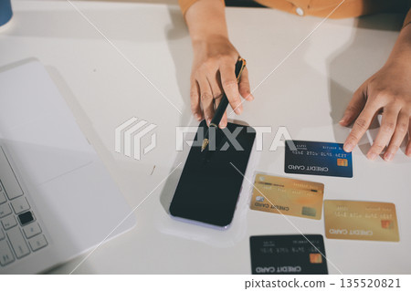 Online payment, Hands of woman holding a credit card and using smart phone for online shopping Online payment, Hands of woman holding a credit card and using smart phone for online shopping 135520821