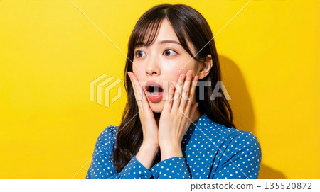 一位表情驚訝的日本女性,背景是黃色。 一位表情驚訝的日本女性,背景是黃色。 135520872