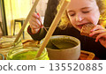Child eating green soup with bread at cafe table 135520885