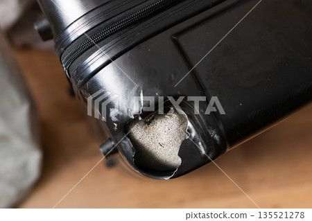 Damaged black suitcase with broken corner after rough baggage handling at airport 135521278