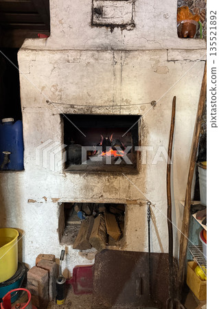 An old Russian stove. Fire is burning in the firebox. A woodpile with firewood is visible at the bottom. 135521892