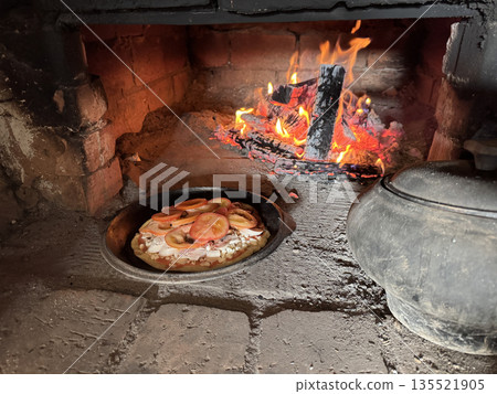 Cooking pizza in a Russian stove next to coals and burning firewood. Cooking food in a vintage stove. 135521905