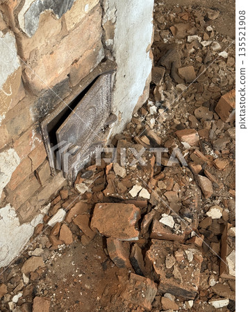 Dismantling a vintage stove in an old house. The firebox door and ash door are visible. The stove is in an emergency condition. Close-up. 135521908