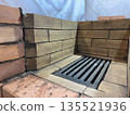 Fresh brickwork of a heating stove. Firebox made of fireclay brick, a cast iron grate installed. Close-up. Fresh brickwork of a heating stove. Firebox made of fireclay brick, a cast iron grate installed. Close-up. 135521936