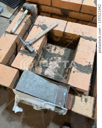 Fresh brickwork of a heating stove. Ash pit of a heating stove. Fresh brickwork of a heating stove. Ash pit of a heating stove. 135521942