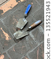 Two trowels on the brickwork of a heating stove base. Two trowels on the brickwork of a heating stove base. 135521943