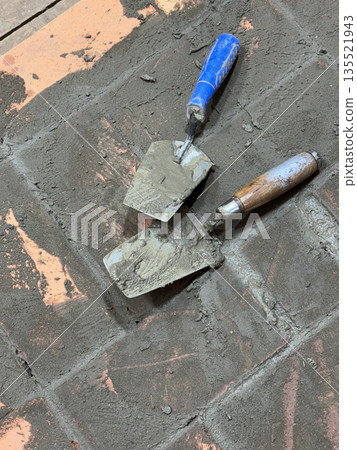 Two trowels on the brickwork of a heating stove base. 135521943