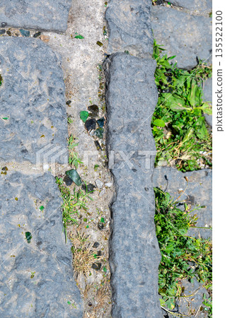 Close-up of a sidewalk in Naples covered with broken glass, reflecting the city ongoing issues with cleanliness and urban waste in certain neighborhoods. 135522100