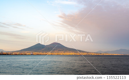 Panoramic view of Mount Vesuvius rising above the city of Naples, Italy, under a clear blue sky, showing the dramatic contrast between urban life and the famous volcano. Panoramic view of Mount Vesuvius rising above the city of Naples, Italy, under a clear blue sky, showing the dramatic contrast between urban life and the famous volcano. 135522113