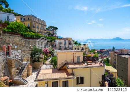 Panoramic top view of Naples rooftops from Castel Sant Elmo, with the sea in the distance and Mount Vesuvius rising above the city on a clear summer day. Panoramic top view of Naples rooftops from Castel Sant Elmo, with the sea in the distance and Mount Vesuvius rising above the city on a clear summer day. 135522115