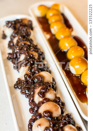 Mitarashi dango and mixed dango with red bean paste arranged in a row on a long, narrow plate Mitarashi dango and mixed dango with red bean paste arranged in a row on a long, narrow plate 135522225