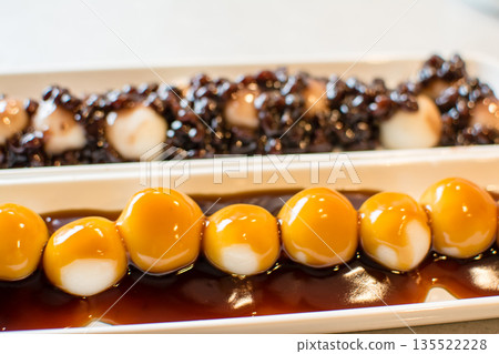 Mitarashi dango and mixed dango with red bean paste arranged in a row on a long, narrow plate Mitarashi dango and mixed dango with red bean paste arranged in a row on a long, narrow plate 135522228
