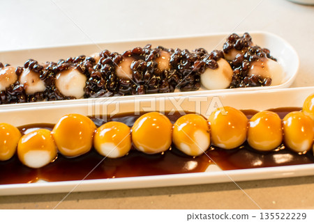 Mitarashi dango and mixed dango with red bean paste arranged in a row on a long, narrow plate Mitarashi dango and mixed dango with red bean paste arranged in a row on a long, narrow plate 135522229