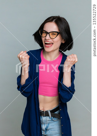 Young woman celebrating win with joyful smile expressing happiness success achievement excitement 135522729