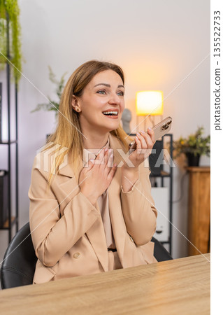 Businesswoman answers smartphone call with good news puts on speaker laughs thanks caller with joy 135522733