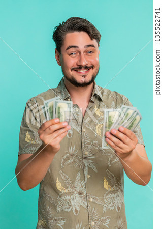 Man counting cash dollars money with satisfied smile expressing financial gain recent income savings Man counting cash dollars money with satisfied smile expressing financial gain recent income savings 135522741