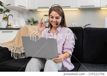 Young woman with headset starts laptop video call with client greets listens asks helpful questions 135522748