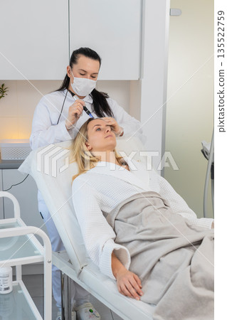 Woman scalp microneedling and injection treatment for hair growth stimulation in trichology clinic Woman scalp microneedling and injection treatment for hair growth stimulation in trichology clinic 135522759