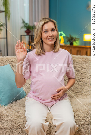 Pregnant woman waving greeting smiling hand raised friendly hello connection welcoming gesture open Pregnant woman waving greeting smiling hand raised friendly hello connection welcoming gesture open 135522783