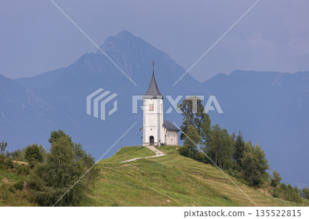 Jamnik, Slovenia. The Jamnik Church is a charming 15th-century chapel in the Kamnik-Savinja Alps near Kranj, breathtaking views of the surrounding mountainous landscape. The Church of St. Primoz 135522815