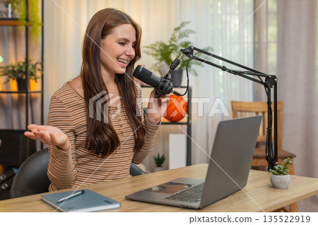 Young woman records vlog on studio mic greets audience shares useful info and invites to subscribe Young woman records vlog on studio mic greets audience shares useful info and invites to subscribe 135522919