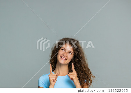 Woman smiling pointing upward presenting advertising promo logo product copy space cheerful gesture Woman smiling pointing upward presenting advertising promo logo product copy space cheerful gesture 135522955