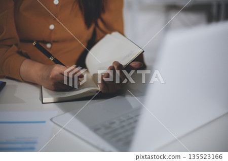 Business woman using calculator to calculate financial report, working at office with laptop computer on table. Asian female accountant or banker making calculations. finances and economy concept Business woman using calculator to calculate financial report, working at office with laptop computer on table. Asian female accountant or banker making calculations. finances and economy concept 135523166