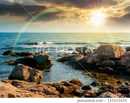 rocky shore of the sea coast under blue sky at sunset. beautiful view of coastal scene in evening light. resort scenery during vacation season in summer. timeless nostalgia book cover with rainbow rocky shore of the sea coast under blue sky at sunset. beautiful view of coastal scene in evening light. resort scenery during vacation season in summer. timeless nostalgia book cover with rainbow 135523435