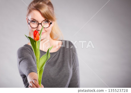 Blonde woman with single tulip. Blonde woman with single tulip. 135523728